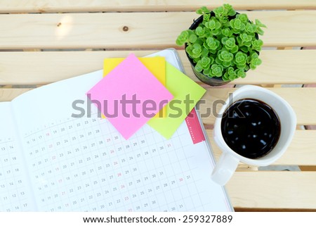 planner book and office tools on the wood table with black coffee