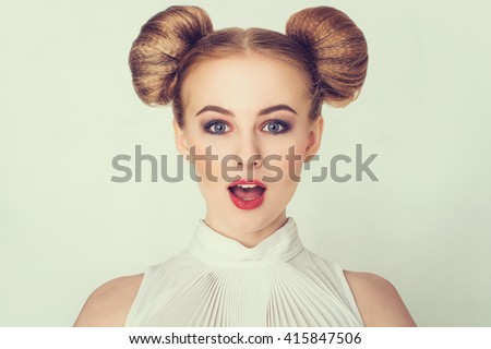 Close-up portrait of surprised beautiful girl with funny hairstyle and open-mouthed.
