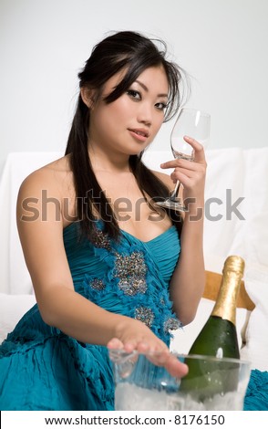 Pretty Asian woman on bed with wine glass and Champagne bucket