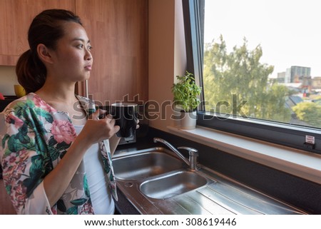 Smart Asian Business Woman Having A Coffee in the Morning in her Kitchen Before She Goes to Work.