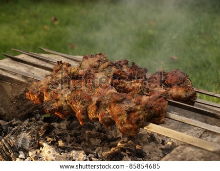 Grilling meat directly over hot coal, smoke background