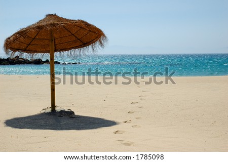 exotic beach near Cadiz, Spain, showing fresh footsteps in the  sand and an umbrella made of coconut fibers.