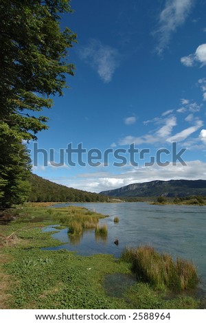picture of a fertile landscape, surrounded by green trees, mountains, en clean river.