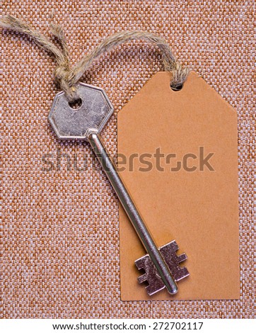 brown paper tag attached to the metal silver key on the brown background