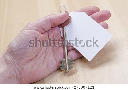 white paper tag attached to the metal silver key in hand