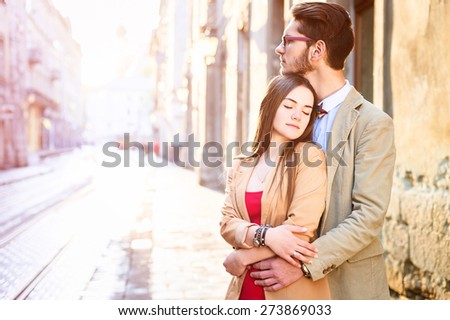 Young fashion elegant stylish couple posing on streets of european city in summer