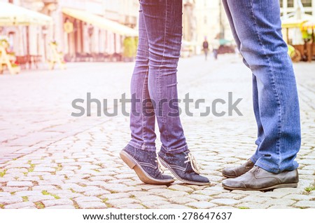Young fashion elegant stylish couple  feet , in love ,their legs stand opposite each other in old city in spring sunny weather, Vintage sunny colors.