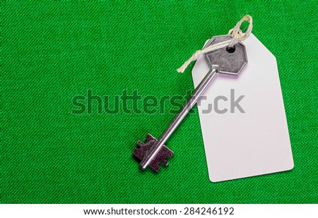 white paper tag attached to the metal silver key on the green background