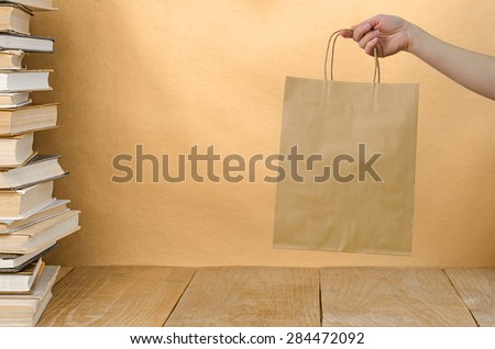 stack book on wooden table and brown kraft bag in hand