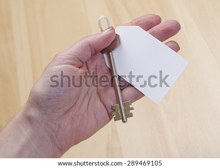 white paper tag attached to the metal silver key in hand