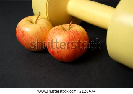 This is an image of a two apples and a yellow dumbbell.