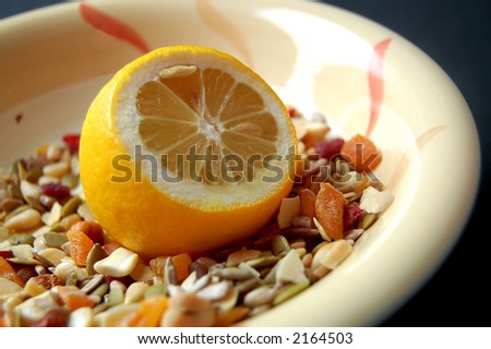 This is an image of a lemon and some country mix fruit/cereal in a bowl.