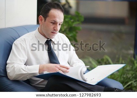 Man at desk in shirt and tie holding his head and worrying about money.