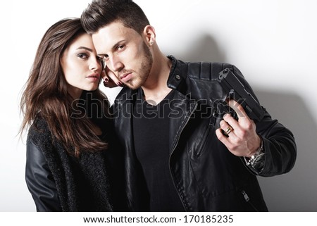 Portrait of young couple in love  with gun posing at studio.Fashion photo.
