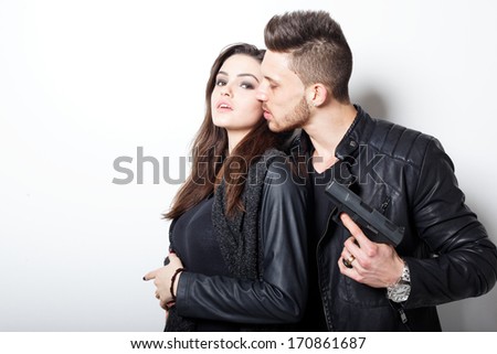 Portrait of young couple in love with gun posing at studio.Fashion photo.