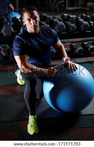 man sitting on a gym ball holding a towel after doing a work out.Low light.
