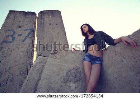 Beautiful young woman posing outdoor in a wall background at sunset.Fashion colors.Wide angle.