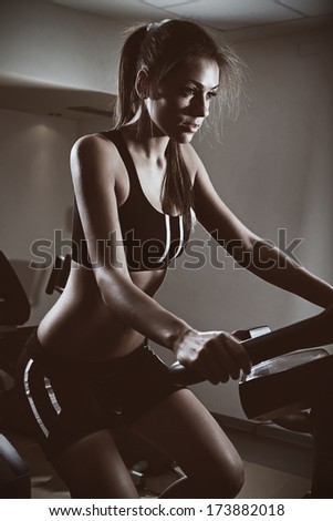 Stationary Bicycles Fitness Girl In A Gym Sport Club.Low Light.Fashion Colors.