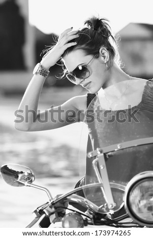 Portrait of smiling girl on scooter holding a helmet - Outdoor on street .Retro shot. Fashion art photo .B&W.