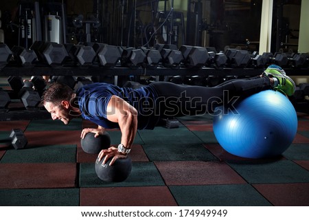 Man At The Gym Doing Exercises For His Abs With A Swiss Ball.Low Light.