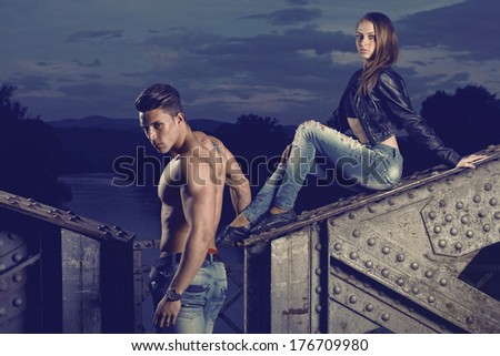 Sexy and fashionable couple wearing jeans, shoot in a grungy location - landscape orientation with copy-space Photo has an intentional film grain) .Fine art.
