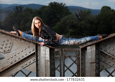Slim gymnast girl in nature, sitting in the splits on the old bridge.Fashion photo.