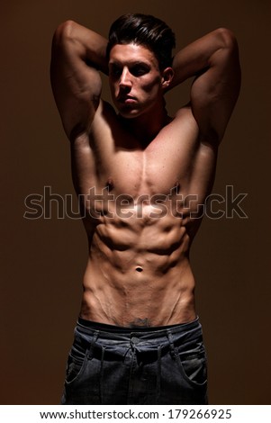 Handsome muscular man. Low light. Focus on abdomen