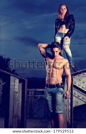 Sexy and fashionable couple wearing jeans, shoot in a grungy location - landscape orientation with copy-space .Fashion colors
