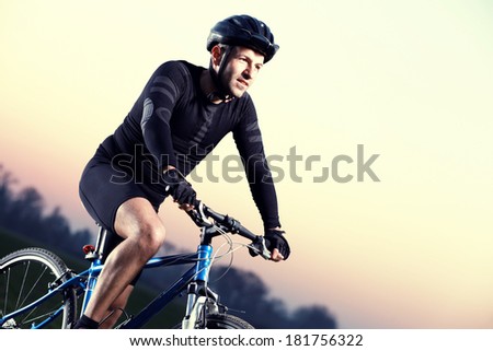 A young male riding a mountain bike outdoor at sunset.Fashion colors.
