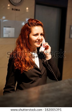 Hotel Concierge .Reception of hotel, desk clerk, woman taking a call and smiling.