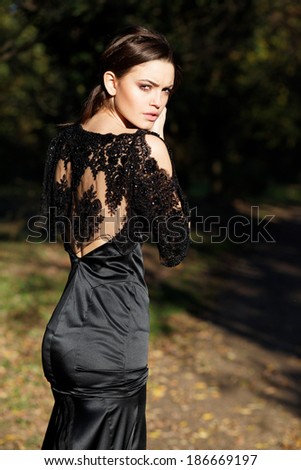 Beautiful slim bride in luxury dress in park on sunset. Romantic girl with glossy hair. Focus on a dress.