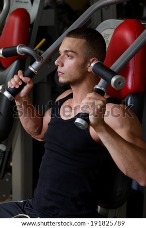 Closeup of a muscular young man lifting weights on dark background .Shallow depth of field with focus on abdominals.