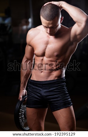 The very muscular handsome sexy guy on black background, naked torso. Shallow depth of field with focus on abdominals.