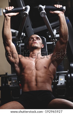 Closeup of a muscular young man lifting weights on dark background .Shallow depth of field with focus on abdominals.