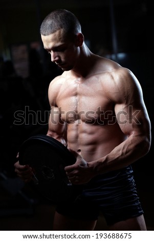 The very muscular handsome sexy guy on black background, naked torso. Shallow depth of field with focus on abdominals.