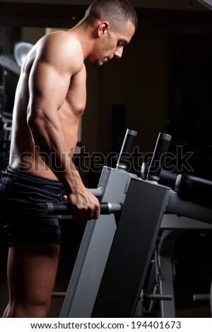 Muscled male model with strong arms.Triceps Workout . Low light.