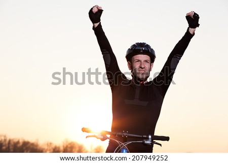 A young male riding a mountain bike outdoor at sunset. Portrait of a handsome man happy