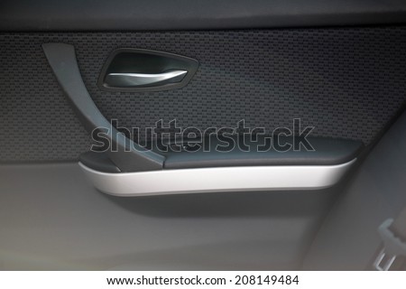 Interior of modern car as background with close-up of doors and manufacturing details. High quality beige and white leather, wood and aluminum.