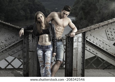 Sexy and fashionable couple wearing jeans, shoot in a grungy location - landscape orientation with copy-space Photo has an intentional film grain) .Fine art.