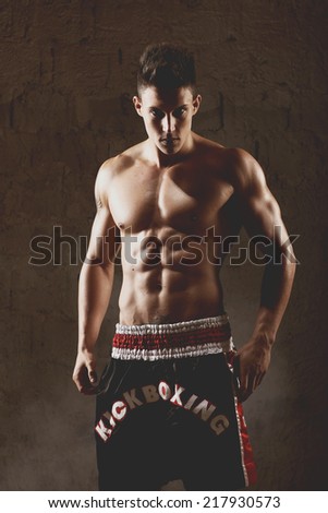 Sportsman kick boxer intense portrait against grey background.