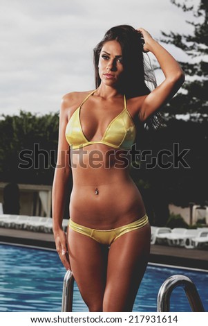 Young, sporty and happy woman posing by the pool, outdoor portrait