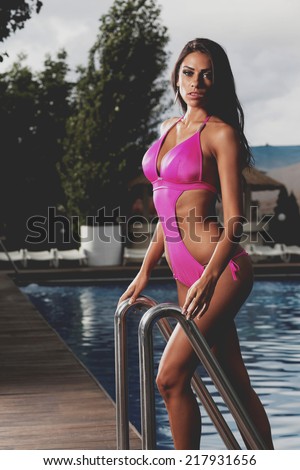 Young, sporty and happy woman posing by the pool, outdoor portrait