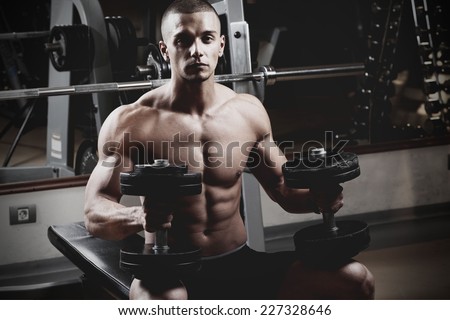 Closeup of a muscular young man lifting weights. Fine art.
