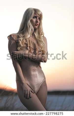 Sexy blond-haired woman over sunset in the summer forest. Young lovely blond model in sexy lingerie. Fashion colors.
