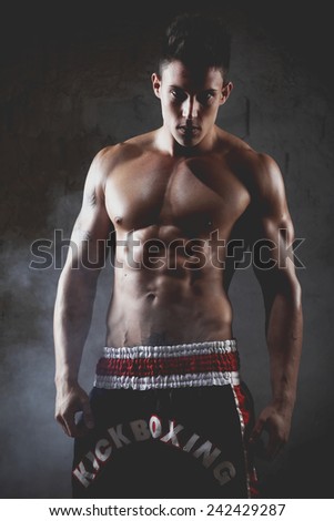 Sportsman kick boxer intense portrait against grey background. Young Boxer fighter .