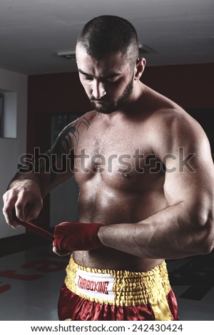 MMA Fighter Practicing Some Kicks With Punching Bag - A Man With A Tattoo In Red Boxing Gloves - Boxing On Black Background - The Concept Of A Healthy Lifestyle - The Idea For The Film About Boxing