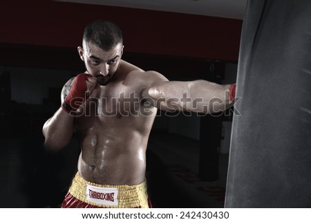 MMA Fighter Practicing Some Kicks With Punching Bag - A Man With A Tattoo In Red Boxing Gloves - Boxing On Black Background - The Concept Of A Healthy Lifestyle - The Idea For The Film About Boxing