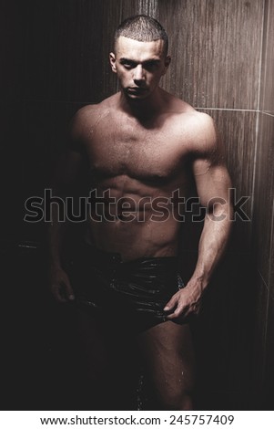Sexy young muscle man in a shower wearing dark underwear