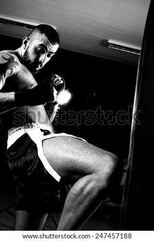 Fighter Practicing Some Kicks With Punching Bag - A Man With A Tattoo In Red Boxing Gloves - Boxing On Black Background - The Concept Of A Healthy Lifestyle - The Idea For The Film About Boxing