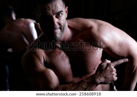 Handsome muscular bodybuilder.Muscular young man lifting weights on dark background